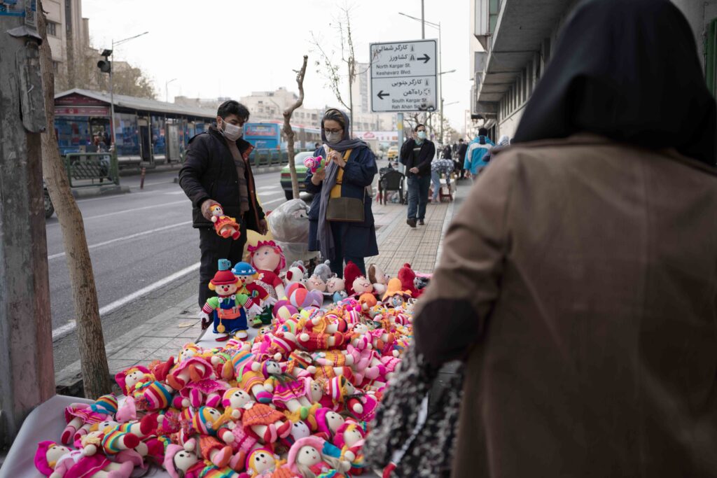 Young woman shopping from a street vendor in front of Cinema Bahman, Enghelab Square, Enghelab Street, Tehran, 2020–2021 — from the Women in Public Space project